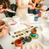Ludzie szkliwią kolorowymi szkliwami naczynia ceramiczne