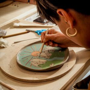 kobieta zdobi talerz techniką sgraffito