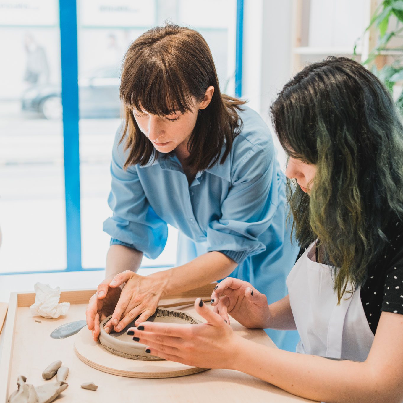 Instruktorka pokazująca uczestniczce warsztatów ceramicznych jak poprawnie lepić z gliny